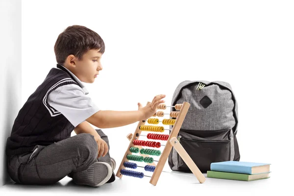 Schoolboy seated on the floor using an abacus — Stock Photo, Image