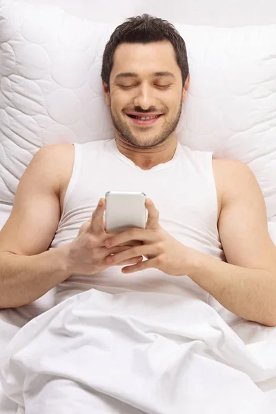 Hombre acostado en la cama y usando un teléfono — Foto de Stock