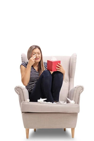 Young woman seated in an armchair crying — Stock Photo, Image