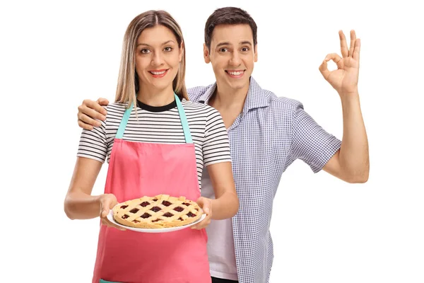 Mulher segurando uma torta e homem fazendo sinal ok — Fotografia de Stock
