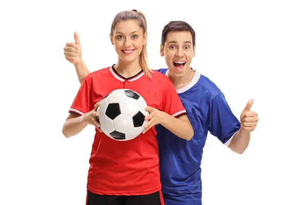 Jugadora de fútbol femenino sosteniendo un balón de fútbol y un jugador de fútbol masculino sosteniendo sus pulgares hacia arriba — Foto de Stock