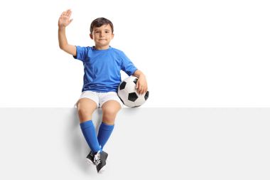 bir panel üzerinde oturan ve sallayarak bir futbol çocukla