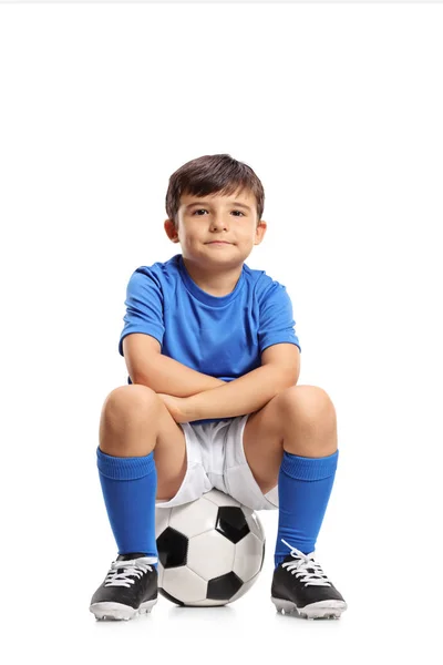 Chłopiec w niebieskim jersey, siedząc na piłce nożnej — Zdjęcie stockowe
