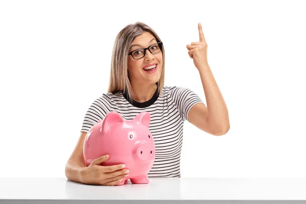 Young woman with a piggybank pointing up — Stock Photo, Image