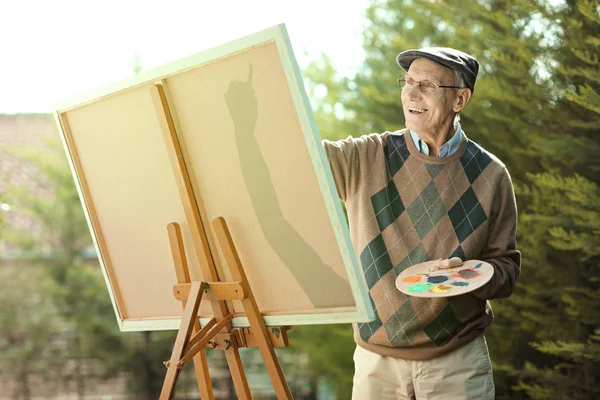 Oudere man schilderen op een doek — Stockfoto