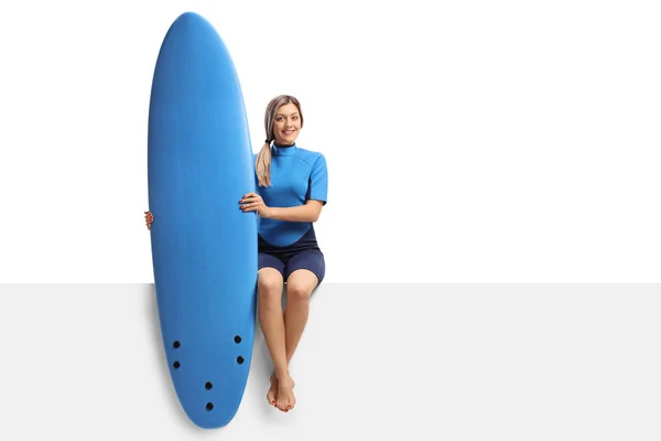 Жіночий серфер з дошкою для серфінгу, що сидить на панелі — стокове фото