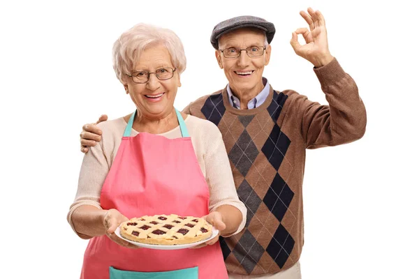 Woman holding freshly baked pie and man making ok sign — Stock Photo, Image