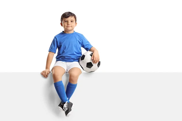 Pequeño futbolista sentado en un panel — Foto de Stock