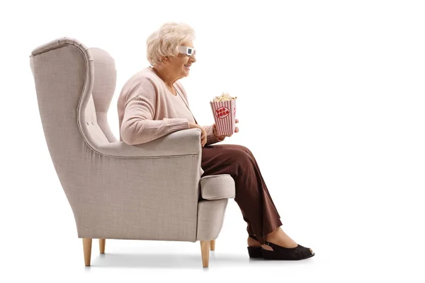 Woman with popcorn and 3D glasses seated in an armchair — Stock Photo, Image