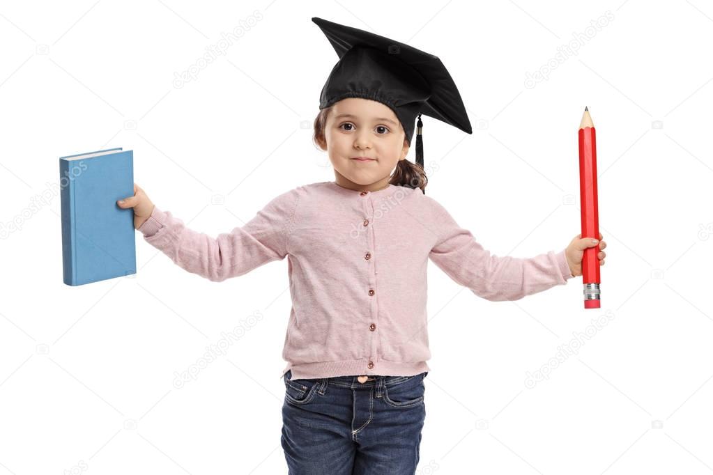 girl wearing a mortarboard holding a book and a pencil
