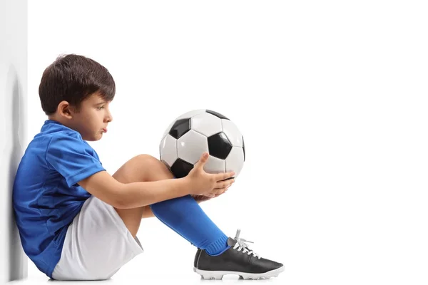 Disappointed little footballer leaning against a wall — Stock Photo, Image