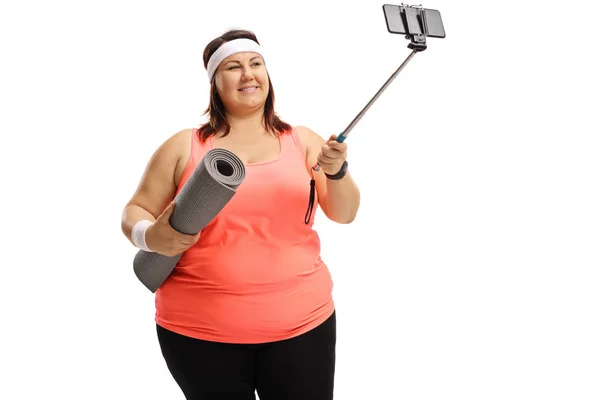 Mulher segurando um tapete de exercício e tomando uma selfie — Fotografia de Stock
