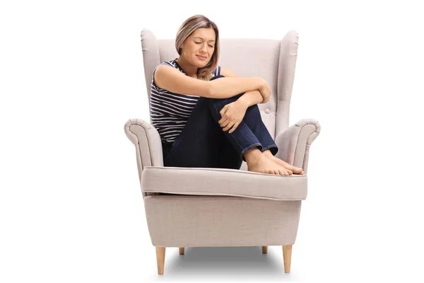 Forstyrret ung kvinde siddende i en lænestol - Stock-foto