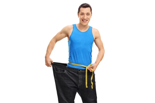 Guy in oversized jeans measuring his waist — Stock Photo, Image