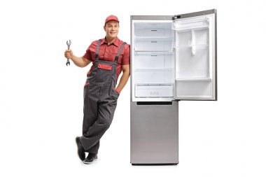Bir İngiliz anahtarı tutan ve bir buzdolabı karşı yaslanmış tamirci
