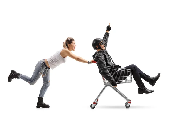 Punk girl pushing a shopping cart with a biker — Stock Photo, Image