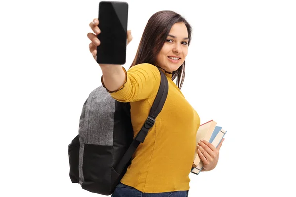 Estudiante con una mochila y libros mostrando un teléfono — Foto de Stock