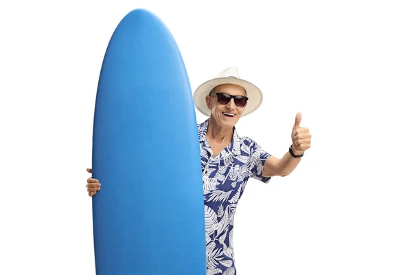 Turista con una tabla de surf haciendo un pulgar hacia arriba signo — Foto de Stock