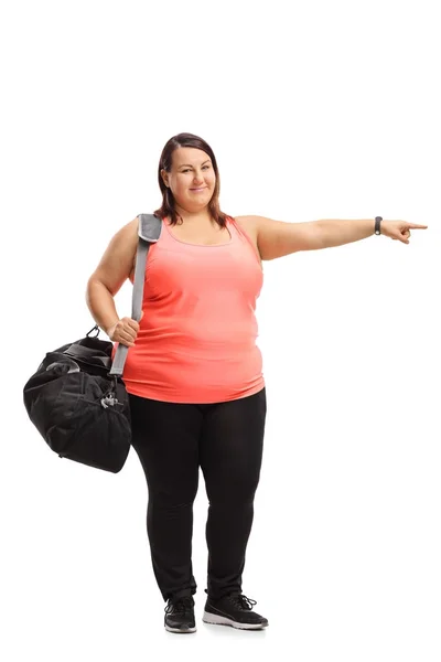 Chica con sobrepeso con una bolsa de deporte apuntando —  Fotos de Stock