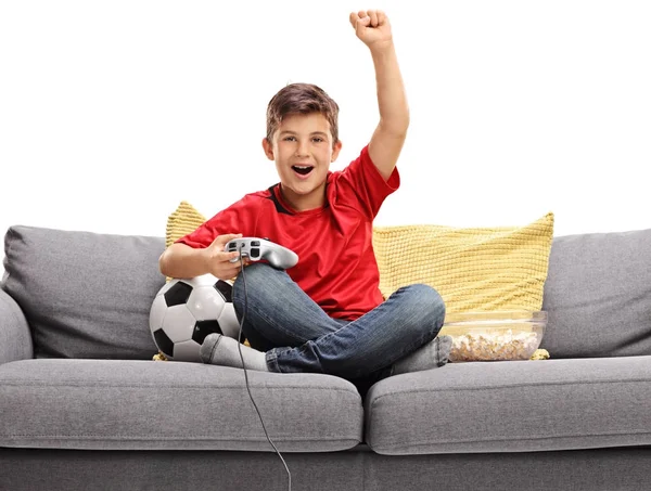 Jongen een spelletje voetbal video op een sofa — Stockfoto