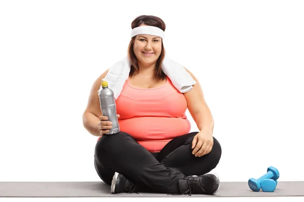 Nadwagę kobieta z ręcznikiem i butelkę na ćwiczenia w pozycji siedzącej — Zdjęcie stockowe