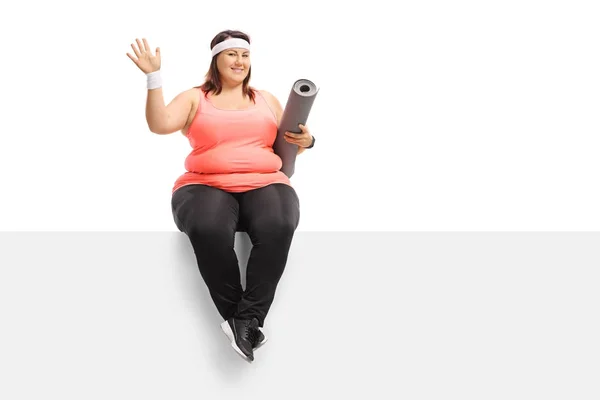 Mujer con sobrepeso con una esterilla de ejercicio ondeando — Foto de Stock