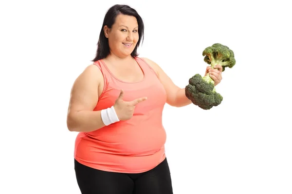 Wanita memegang brokoli dumbbell dan menunjuk — Stok Foto