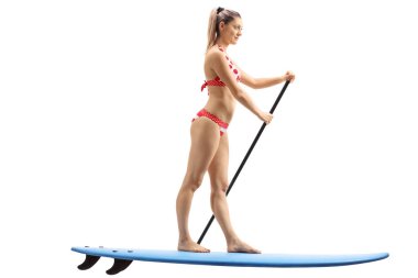 Sörf tahtası üzerinde duran ve kürek çekmeye genç kadın