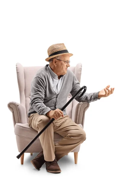Man with a cane sitting in an armchair and talking — Stock Photo, Image