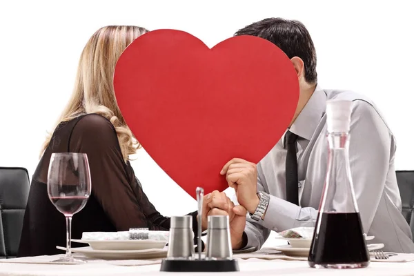 Par kyssar bakom ett rött hjärta — Stockfoto