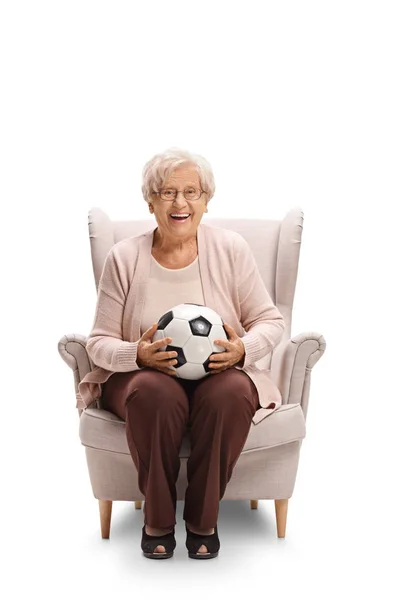 Cheerful woman with a football sitting in an armchair — Stock Photo, Image