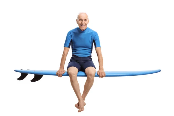 Älterer Surfer sitzt auf einem Surfbrett und lächelt — Stockfoto