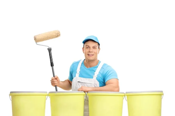 Pintor com um rolo de tinta apoiado em baldes de cor — Fotografia de Stock