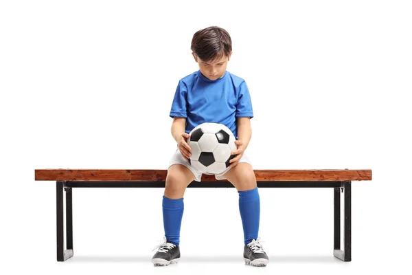 Грустный футболист, сидящий на деревянной скамейке — стоковое фото