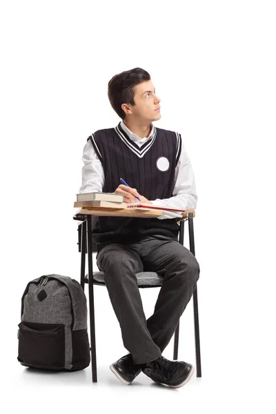 Студент, сидящий в школьном кресле, записывает — стоковое фото