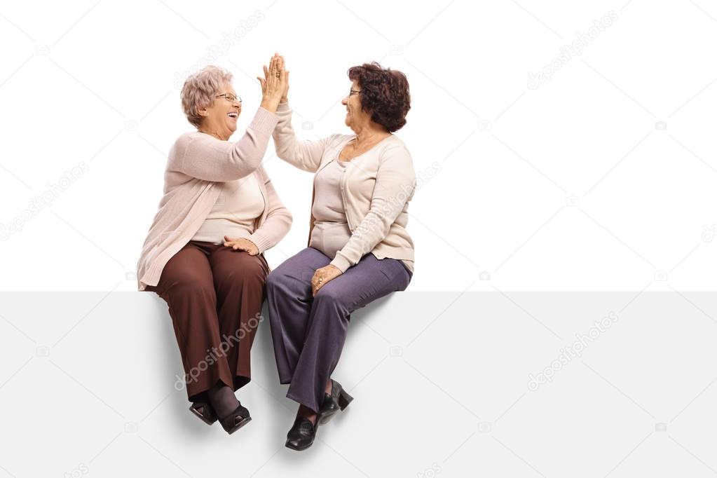 women sitting on a panel and high-fiving each other