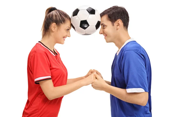 Female and a male footballers holding a football between their heads — Stock Photo, Image