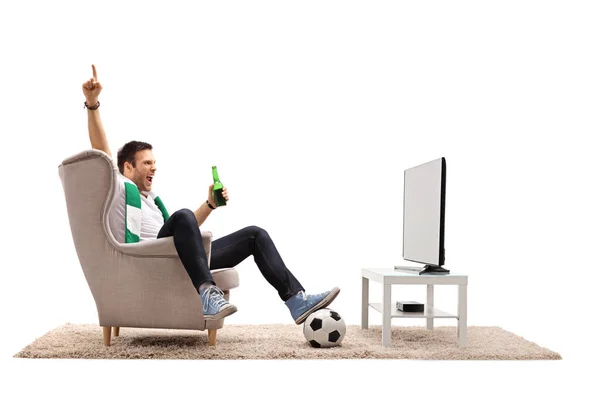 Mann som ser på fotball på TV og peker opp – stockfoto
