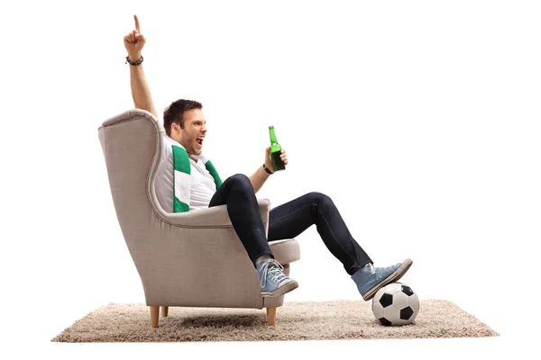 Ventilador de fútbol sentado en un sillón apuntando hacia arriba — Foto de Stock