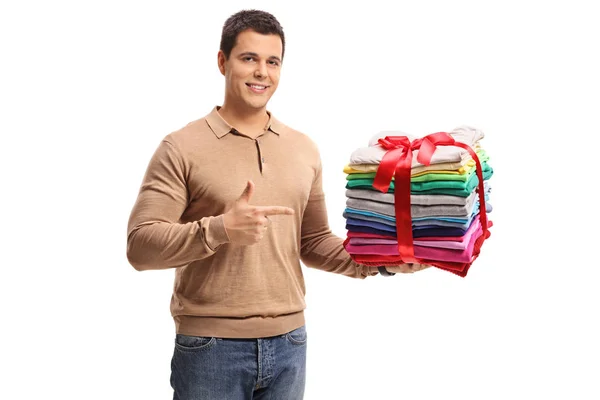 Man holding a stack of clothes and pointing — Stock Photo, Image