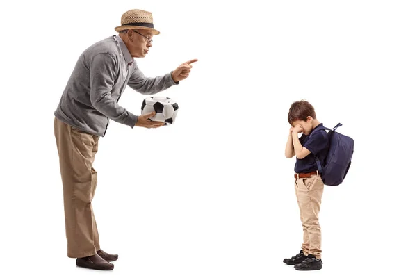 Man with a deflated football scolding a boy — Stock Photo, Image