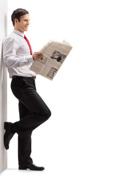 Guy reading a newspaper and leaning against a wall — Stock Photo, Image