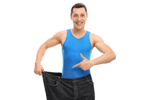 Guy wearing a pair of oversized jeans and pointing — Stock Photo, Image