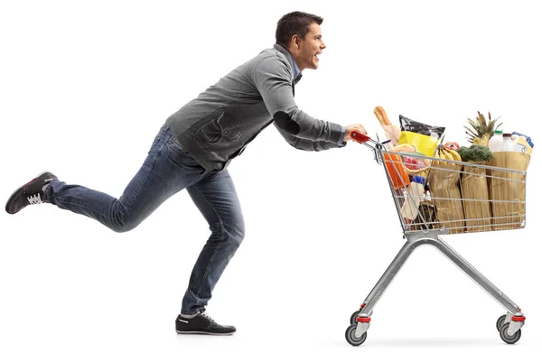 Ragazzo correre e spingere un carrello della spesa con generi alimentari — Foto Stock