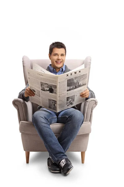 Νεαρός άνδρας με μια εφημερίδα που κάθεται σε μια πολυθρόνα — Φωτογραφία Αρχείου