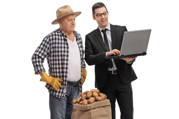 Homme d'affaires montrant quelque chose sur un ordinateur portable à un agriculteur — Photo