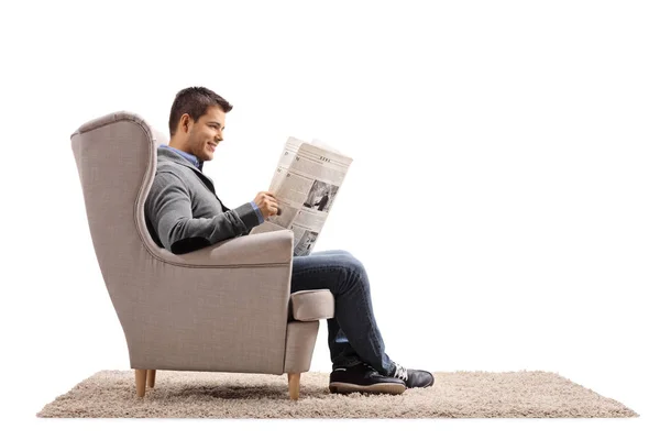Парень сидит в кресле и читает газету. — стоковое фото