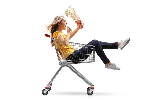 Donna con una scatola di popcorn a cavallo all'interno di un carrello della spesa — Foto Stock