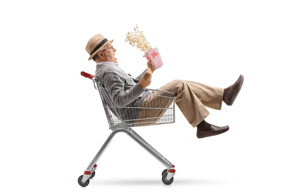 Homem com uma caixa de pipocas montando dentro de um carrinho de compras — Fotografia de Stock