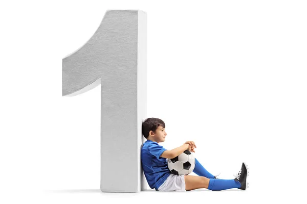 Weinig voetballer tegen een kartonnen nummer één — Stockfoto